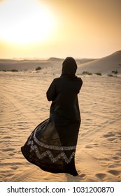 Woman in a burka Burqa walking over a middle eastern desert during sunset. - Shutterstock ID 1031200870