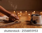 woman burning aroma stick for meditation and yoga in cozy warm atmosphere of room