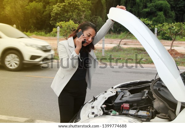 Woman business calling phone fore help from the\
broken car. Woman business at broken car on road and calling on\
cellphone for help.