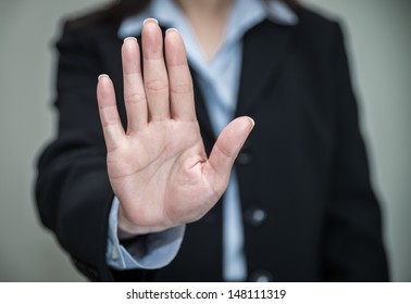 Woman in business suit showing her palm in grey background
