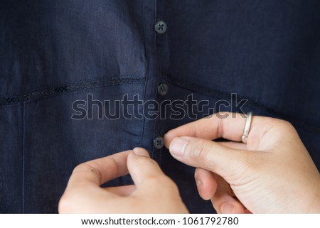 Woman buttoning her blue clothes.close up