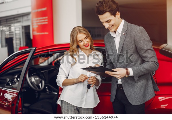 Woman buying the car. Lady in a car salon. Manager\
with a client