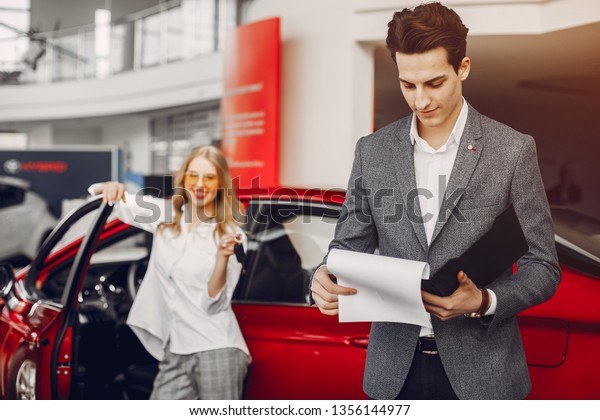 Woman buying the car. Lady in a car salon. Manager\
with a client