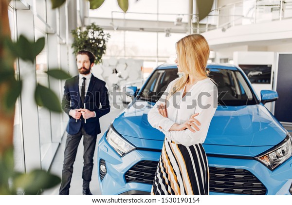 Woman buying the car. Lady in a car salon. Manager\
with a client