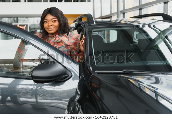 Woman buying the car. Lady in a car salon. Elegant\
black girl