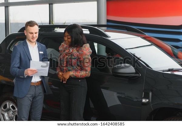 Woman buying the car. Lady in a car salon. Elegant\
black girl