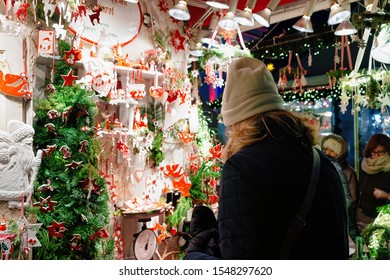 Woman Buying Ceramics Christmas Tree Decorations On Night Market In Gendarmenmarkt In Winter Berlin, Germany. Advent Fair And Bazaar Stalls With Craft Items.