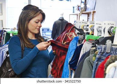 Woman Buying Children's Clothes In Charity Shop