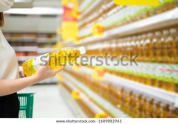 Woman buying cooking\
oil in supermarket