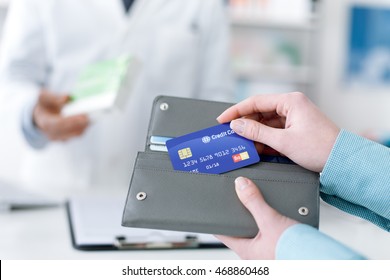 Woman buying drugs and medical products in the pharmacy, she is taking the credit card from the wallet - Powered by Shutterstock