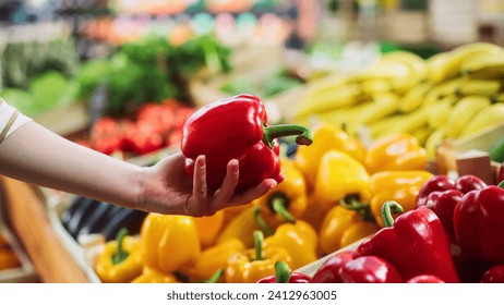 Woman Buying Fresh Vegetables from a Local Farm Market Stall. Close Up Footage Focusing on a Female Hand Choosing a Ripe Red Bell Pepper from a Selection on a Stand with Natural Produce - Powered by Shutterstock