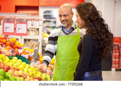 A Woman Buying Groceries Receiving Help From A Store Clerk