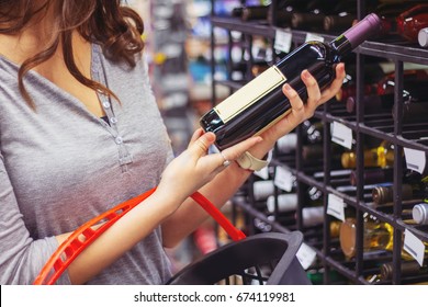 Woman Buying And Holding Bottle Of Wine