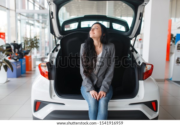 Woman buying\
new car, lady near the opened\
trunk