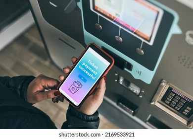 Woman buying ticket at ticket machine paying using mobile payment app on smartphone. Female buying bus public transport ticket in vending machine. Purchasing car parking ticket using mobile phone - Powered by Shutterstock