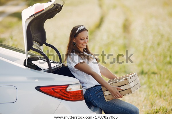 Woman by the car. Lady in a white t-shirt. Woman\
with wood box.