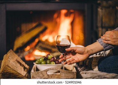 Woman By The Fireplace. Woman In Woollen Socks Taking A Glass Of Red Wine Relaxing By The Cozy Fireplace. Snug Winter Evening. 