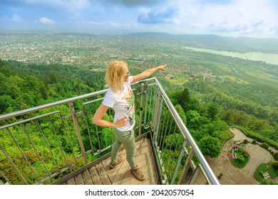 Woman by Zurich cityscape on a Swiss lookout tower on Uetliberg mountain in Swiss plateau of Switzerland. Canton of Zurich. Carefree girl with open arms looking panorama of Zurich with lake at sunset.