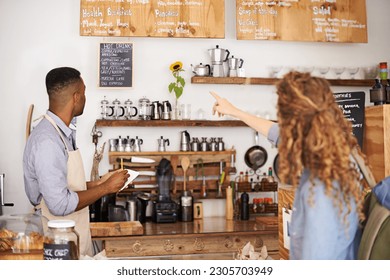 Woman, cafe and pointing at menu on wall with barista, notes and decision for good customer experience. Male waiter writing, lady and talking with choice, thinking and order special from bakery shop - Powered by Shutterstock