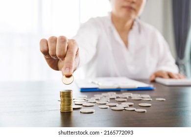 woman calculating expenses and having ideas for saving money, She is pressing the calculator and picking up a coin, saving money or savings concept.