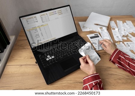 Woman calculating her income and personal expenses. Lot of bills, calculator and charts on the laptop screen. Home office  Foto stock © 