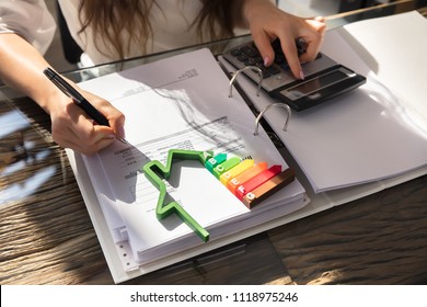 Woman Calculating Invoice With Energy Efficient Chart And House Silhouette In Office