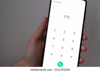 Woman calling 112 for an emergency. It says "urgent call" on the screen. Closeup of a hand holding smartphone or smart phone. 112: Emergency call number in European Union countries and Turkey. - Shutterstock ID 2112701249