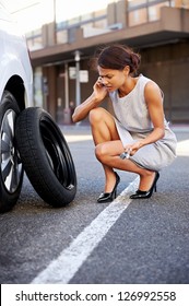 Woman Calling For Assistance With Flat Tire On Car In The City