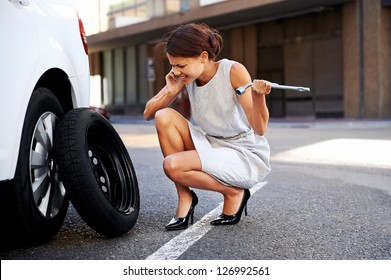 Woman Calling For Assistance With Flat Tire On Car In The City