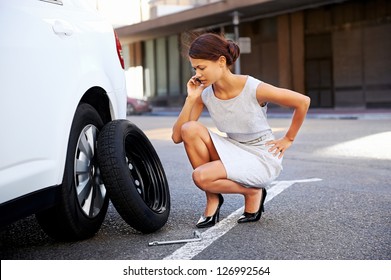 Woman Calling For Assistance With Flat Tire On Car In The City