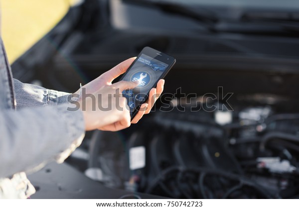 Woman calling a car assistance service with\
her smartphone, her car has broken\
down