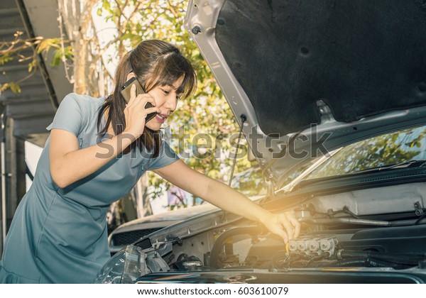 Woman calling emergency service near her broken\
car. (vintage color tone\
image)
