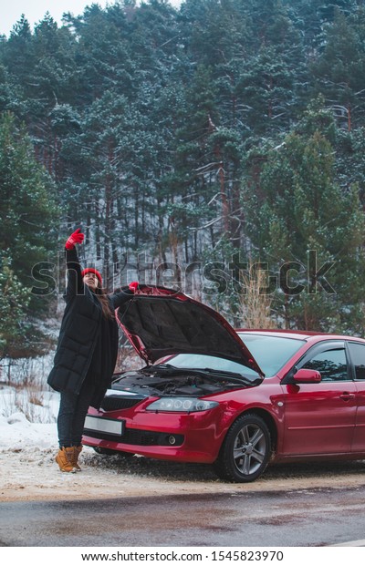 woman calling for help with broken down car at\
winter highway