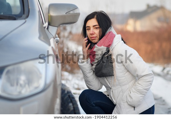 Woman calling for help to fix the car in winter on\
the road