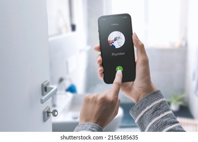 Woman calling a plumber on her smartphone, she has a water leak in the bathroom