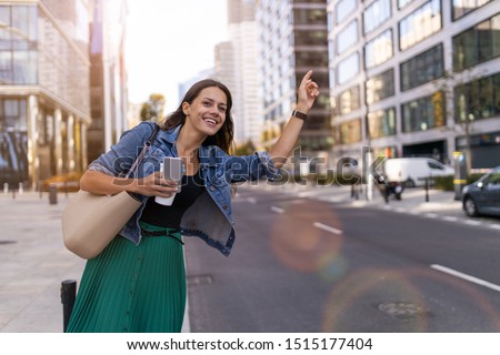 Woman calling taxi on city street
