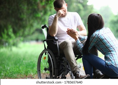 Woman Calm Down Man In Wheelchair. Disabled Person Sit In Wheelchair, Cover His Face With His Hand And Get Upset. State Support For Children Raising Children With Disabilities. Benefits, Rights And