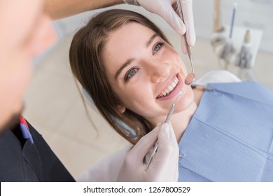 The woman came to see the dentist. She sits in the dental chair. The dentist bent over her. Happy patient and dentist concept. 