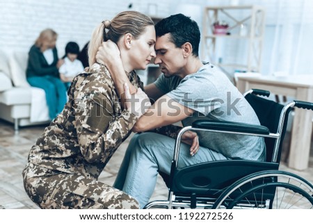 A Woman In Camouflage Goes To Military Service. Leaving To Army. Farewell With Family. Camouflage Uniform. Husband On Wheels Farewell. Saying Goodbye. Guard Of Peace. Soldier Emotion.