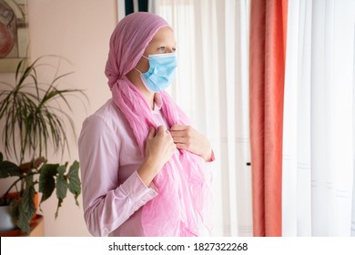 Woman With Cancer, Pink Headscarf And Mask Looking Out The Window