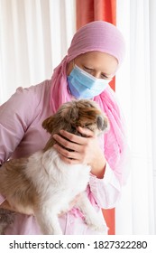 Woman With Cancer, Pink Headscarf And Mask Hugging Her Pet