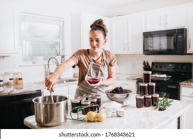 Woman Canning Homemade Blackberry Jam In White Kitchen