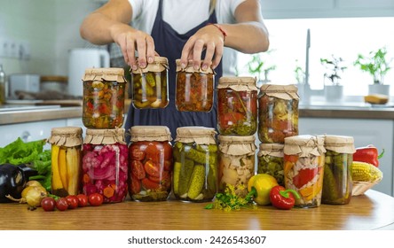 Woman canning vegetables in jars in the kitchen. Selective focus. Food. - Powered by Shutterstock