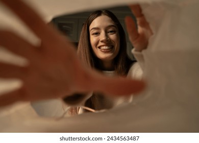 A woman is captured in a moment of joy when she opens a paper bag, eagerly stretching out her hands to the contents. - Powered by Shutterstock