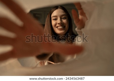 A woman is captured in a moment of joy when she opens a paper bag, eagerly stretching out her hands to the contents.