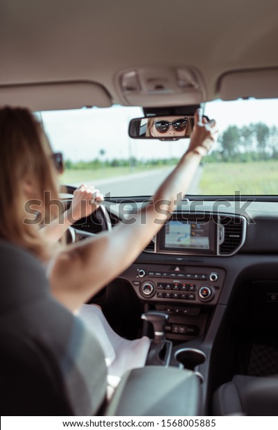 woman in\
car, adjusts and rearview mirror, driving safety in car, parking\
and rear traffic. Reverse parking in car. Looks back row of seat,\
checking passengers and young children in\
seat
