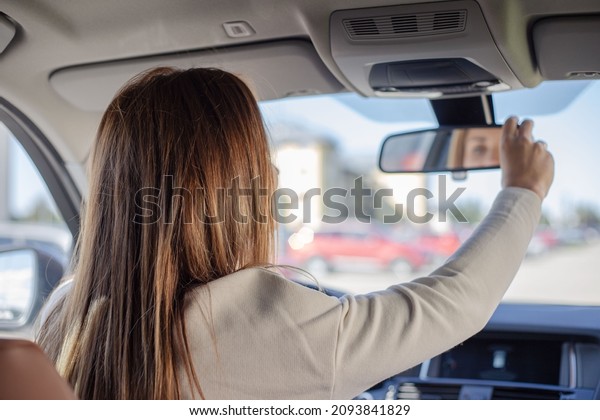 A woman in the car, checks the back row of the\
passengers\' seats for children or guests, rear row mirror and the\
type of seats, rear-view parking of the car. Setting a rearview\
mirror.