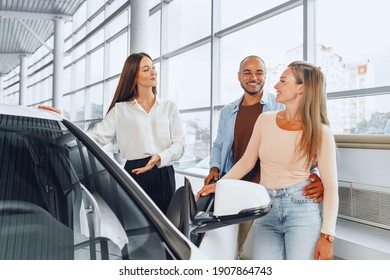 Woman Car Dealer Explaining To Buyers Features Of Their New Car