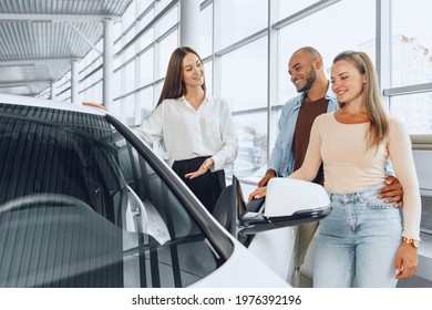 Woman Car Dealer Explaining To Buyers Features Of Their New Car