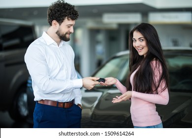 Woman At A Car Dealership Buying An Auto, The Sales Rep Giving Her The Key